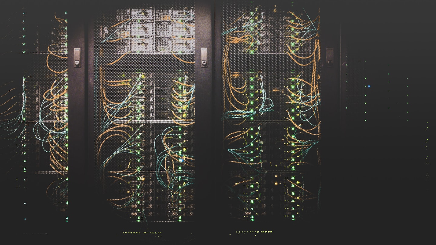 Server racks with blinking green lights and colorful cables.